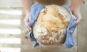 Brot und Brötchen selber backen in Marsberg Eine Person hält einen Brotlaib in einem Trockentuch in den Händen