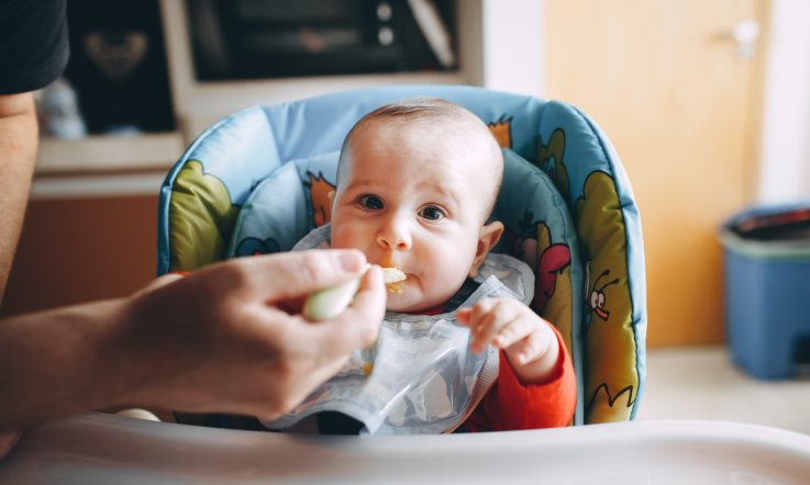 Baby im Hochstuhl wird gefüttert