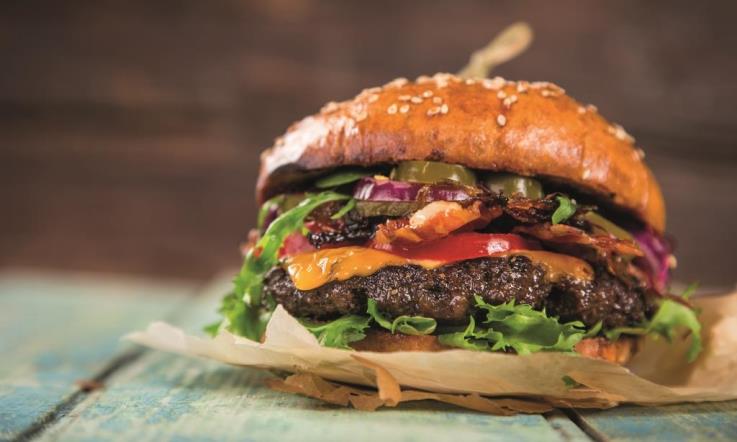 Eltern-Kind-Kurs Burger machen in Olsberg Ein Burger mit vielen Schichten auf einem Holztisch