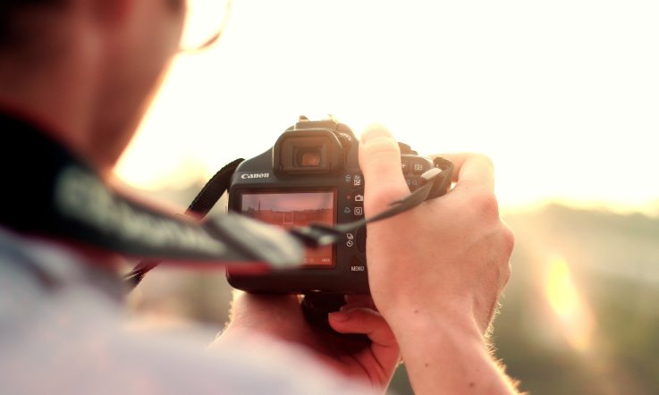 Mann mit Digitalkamera in der Hand fotografiert den Sonnenuntergang